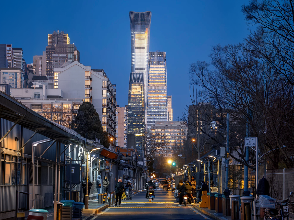 Beijing hutong street at dusk with a skyscraper in the distance