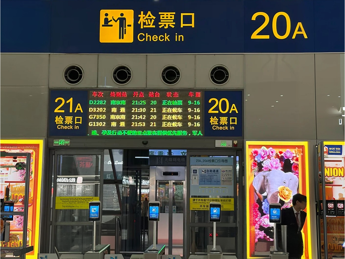 Ticket gates and electronic train information screens at a high-speed rail station