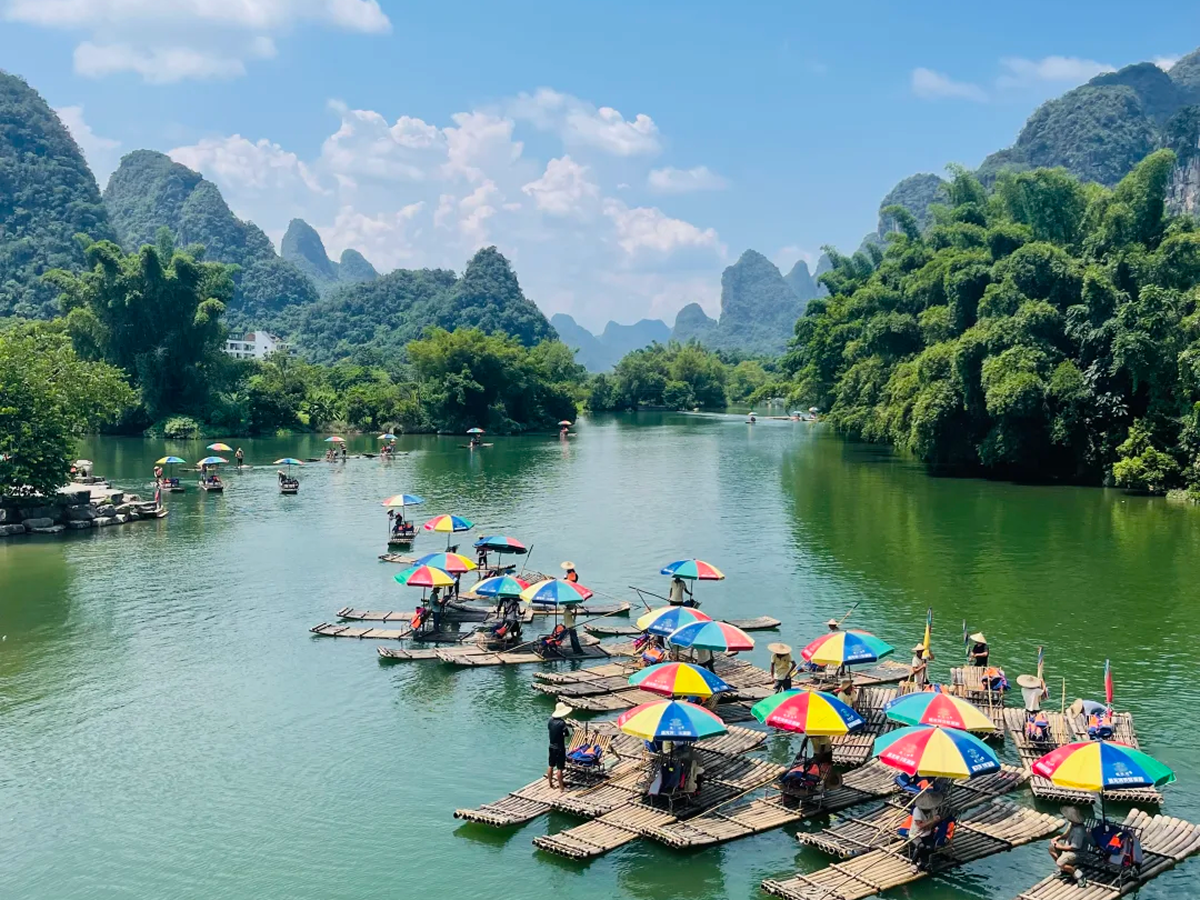 Bamboo rafts with sun umbrellas on the Yulong River among karst hills