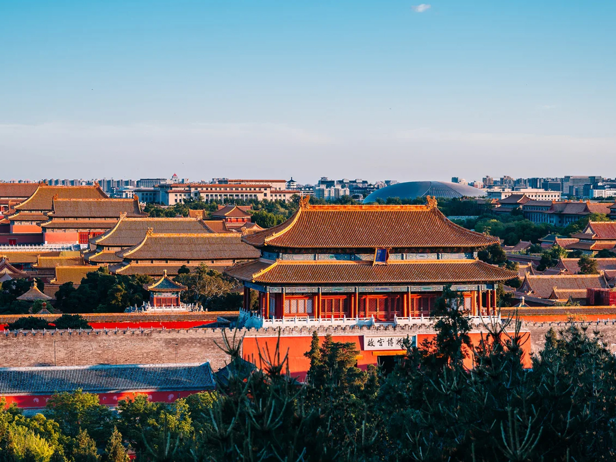 Red walls and yellow roofs of the Palace Museum with city skyline