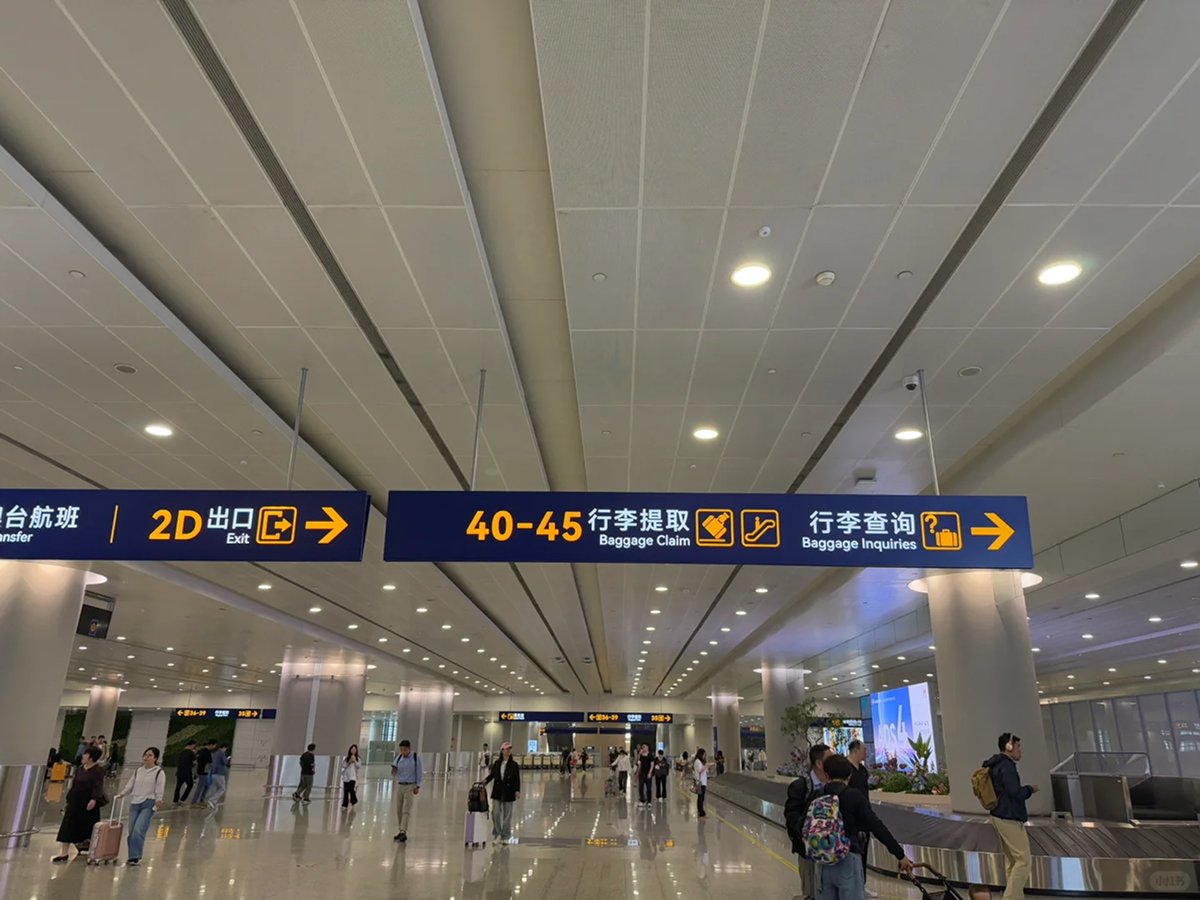 Bright baggage claim and exit signs in a Shanghai airport arrival hall