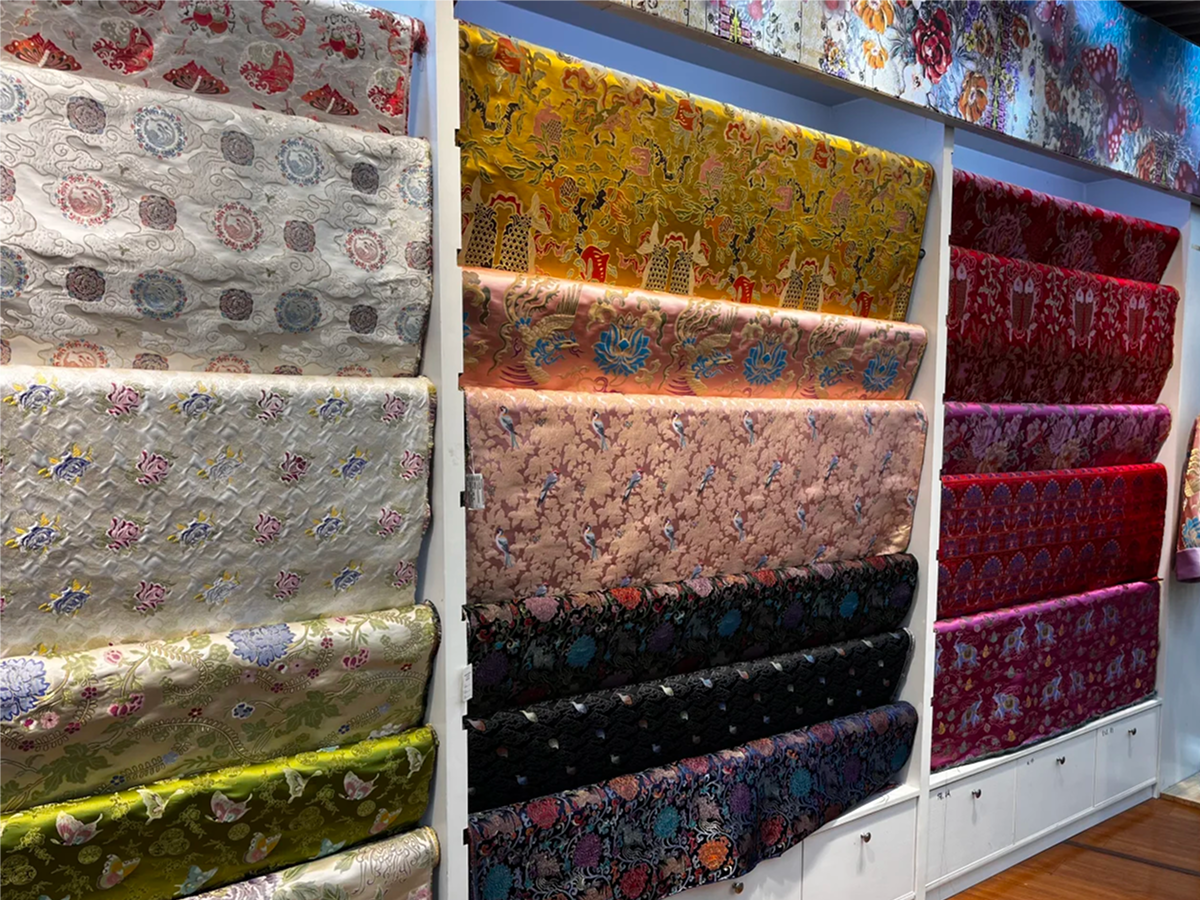 Rolls of patterned Chinese silk fabric on display shelves
