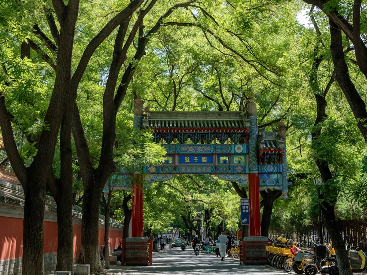 Tree-lined Guozijian Street with a traditional archway